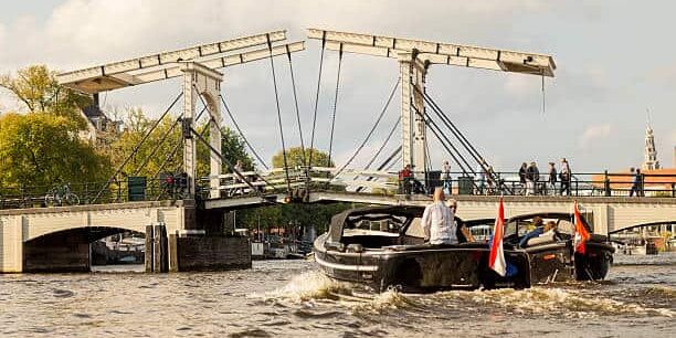 two boats on their way to pass below the magere brug crossing the amstel river.